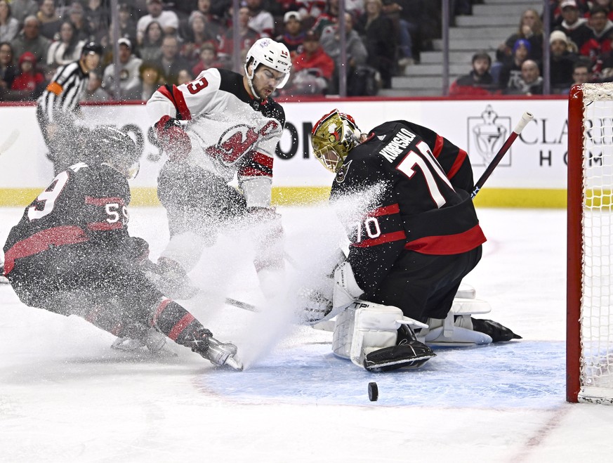 Ottawa Senators goaltender Joonas Korpisalo (70) makes a save in front of left wing Angus Crookshank (59) and New Jersey Devils center Nico Hischier (13) during the first period of an NHL hockey game, ...