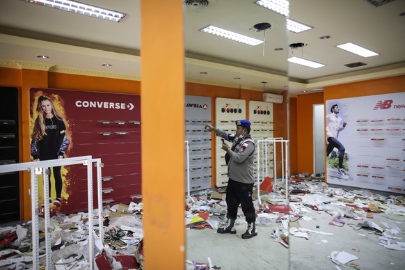 epa07068665 An Indonesian police officer inspects an empty shoes store after looting at a shopping area in Palu, Central Sulawesi, Indonesia, 04 October 2018. According to reports, at least 1,407 peop ...