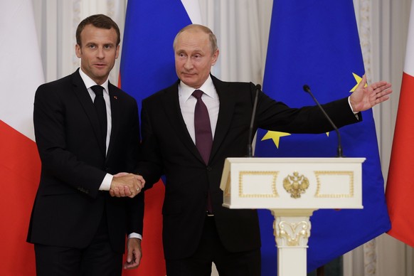 Russian President Vladimir Putin, right, gestures as he shakes hands with French President Emmanuel Macron after their joint news conference following the talks at the Konstantin palace with the statu ...