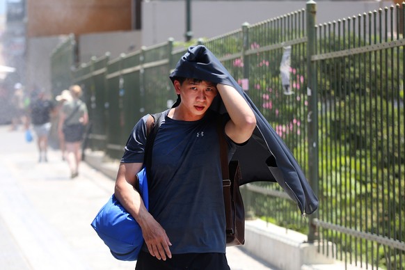 epa10743503 A man tries to protect himself from the hot sun amid high temperatures in Athens, Greece, 13 July 2023. Extremely high temperatures with a potentially serious impact on health are forecast ...