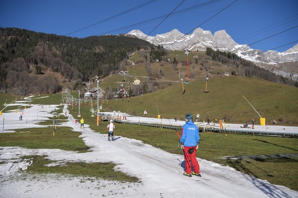 epa10394277 People enjoy themselves on a slope of artificial snow, in Engelberg, Switzerland, 07 January 2023. The Swiss alps are confronted with a lack of snow and warm temperatures. EPA/URS FLUEELER