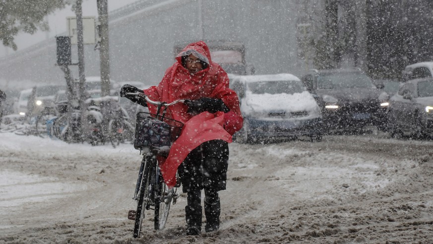 Eine Frau schiebt ihr Velo im Schnee-Matsch.