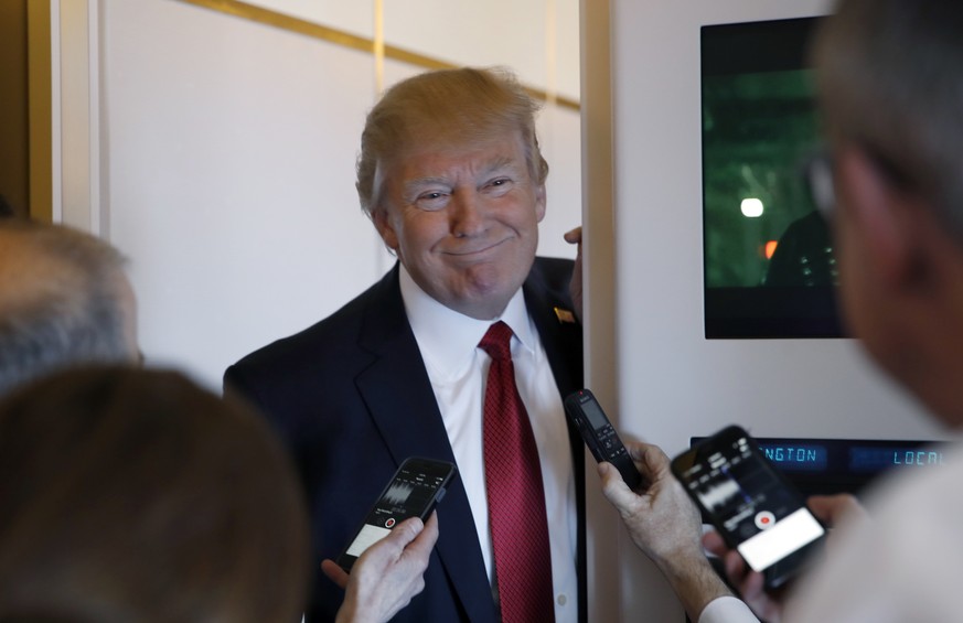 President Donald Trump smiles as he meets with reporters on Air Force One while in flight from Andrews Air Force Base, Md., to Palm Beach International Airport, Fla., Thursday, April 6, 2017. (AP Phot ...