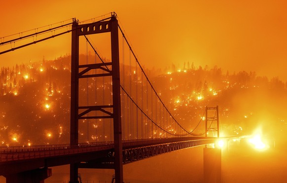 FILE - In this Sept. 9, 2020, file image taken with a slow shutter speed, embers light up a hillside behind the Bidwell Bar Bridge as the Bear Fire burns in Oroville, Calif. Deadly wildfires in Califo ...