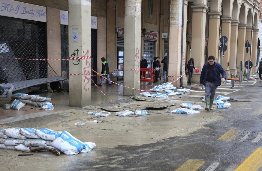 Mud and sand bags lie on the side of a street as a shop is damaged after the Ravone underground canal overflowed, in Bologna, Italy, Wednesday, May 3, 2023. According reports one person in reported de ...