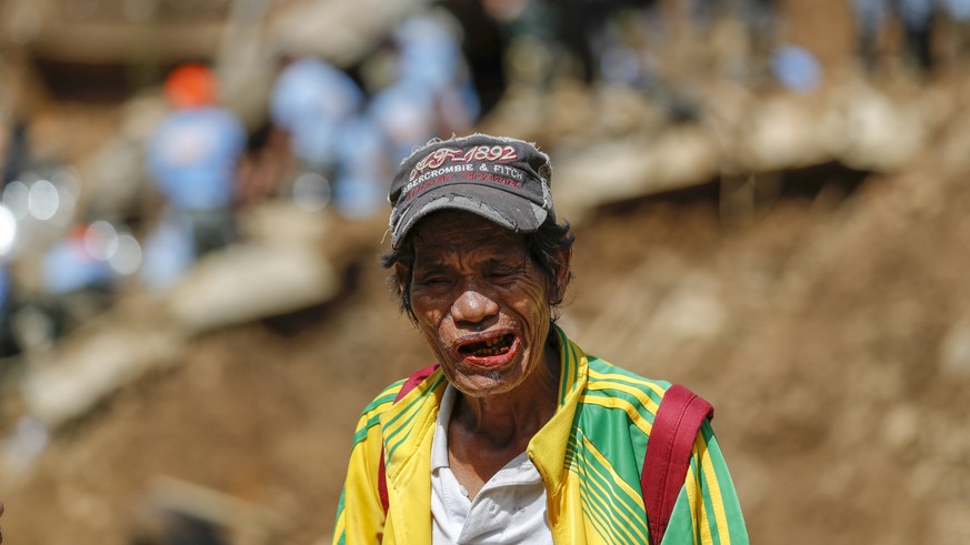 epa07026427 A relative of s landslide victim, caused by Typhoon Mangkhut, waits as people continue to work during rescue and retrieval operations in Ucab village, Itogon town, Benguet Province, Philip ...