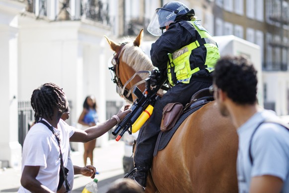 epa12321839 A mounted police officer confiscates a water blaster from a carnival reveller during the Notting Hill Carnival adults parade day in London, Britain, 25 August 2025. The Notting Hill Carniv ...