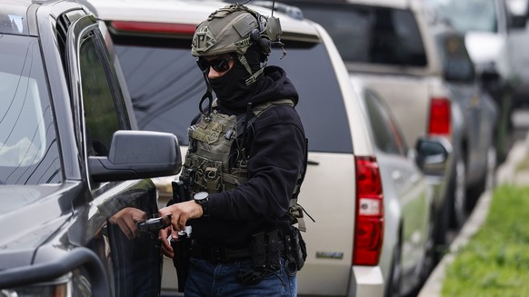 epa12669130 Immigration and Customs Enforcement agents and other law enforcement officials investigate a reported federal agent-involved shooting near the intersection of 126th Street and Mona Bouleva ...