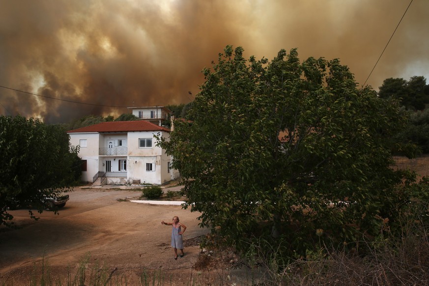 epaselect epa09397651 A woman speaks to media during a wildfire in Viliza village in the area of Ancient Olympia, Peloponnese, Greece, 05 August 2021. Fires continued to rage in Olympia, in the Pelopo ...