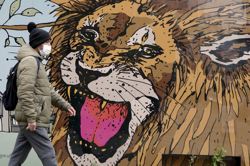 A pedestrian wears a mak as they pass a mural in London, Tuesday, Nov. 30, 2021. With the emergence of the omicron variant the British government are requiring people to wear masks in shops and on pub ...