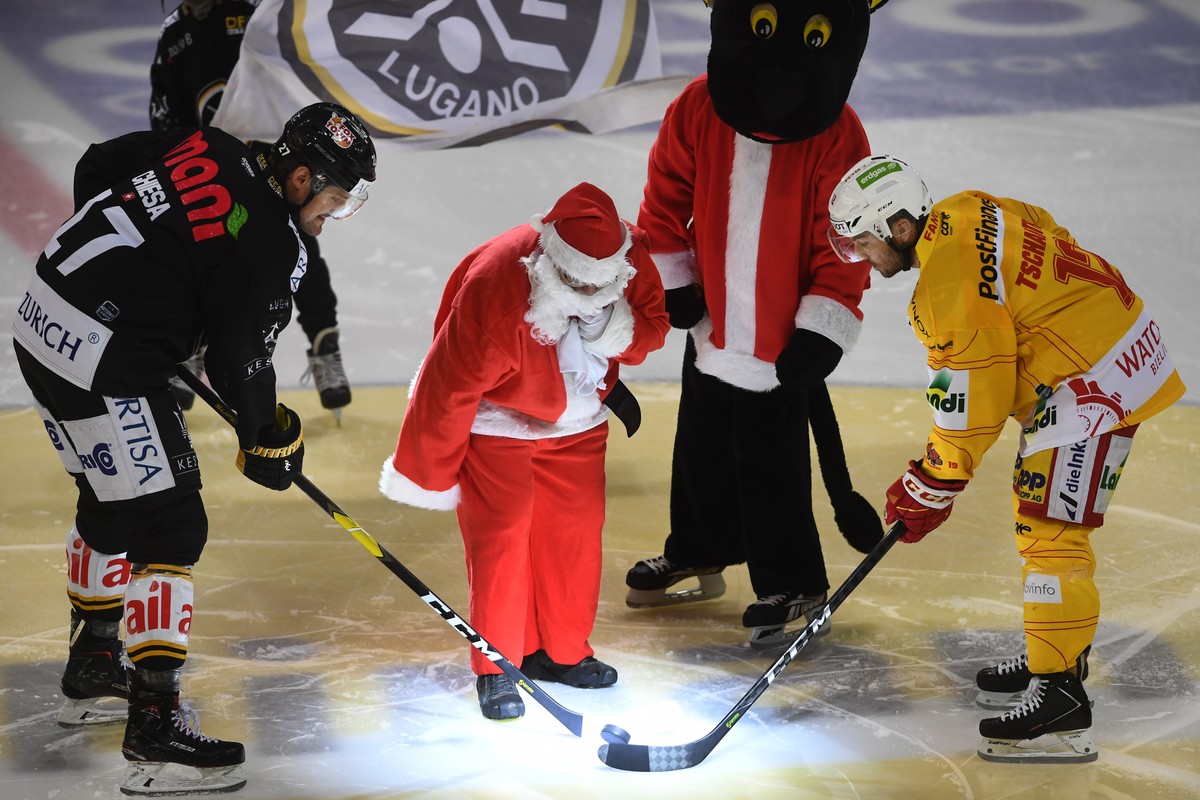 Lugano's player Alessandro Chiesa, left, during the face off with Santa Claus, center, and Biel's player Mathieu Tschantre, right, during the preliminary round game of National League Swiss  ...