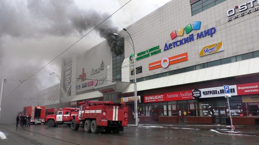 epa06628913 A handout photo made available by the Russian Emergencies Ministry shows fire fighters climbing up onto a top floor of a shopping mall Zimnyaya Vishnya on fire in the Siberian city of Keme ...