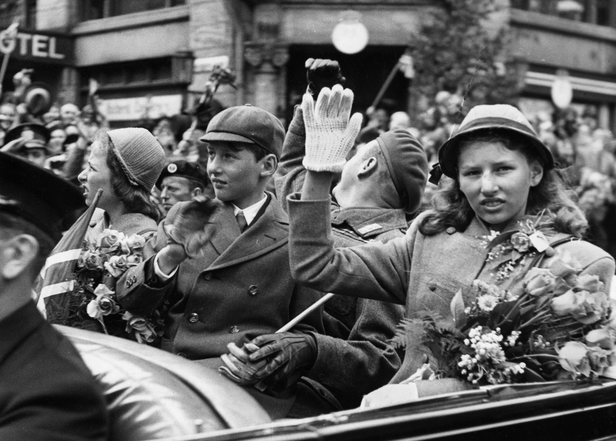 ARKIV 1945 Norska prinsessan Astrid, av Norge t.h. vinkar med blommor i handen i bilen tillsammans med sina syskon prinsessan Ragnhild, t.v. och kronprins Olav, vid Kung Haakons aterkomst till Norge e ...