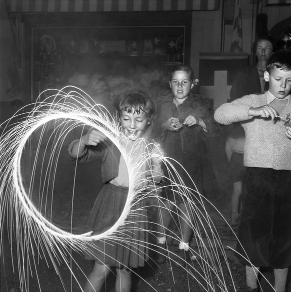 Kinder spielen am Nationalfeiertag des Jahres 1953 in Le Sepey im Kanton Wallis mit Wunderkerzen.