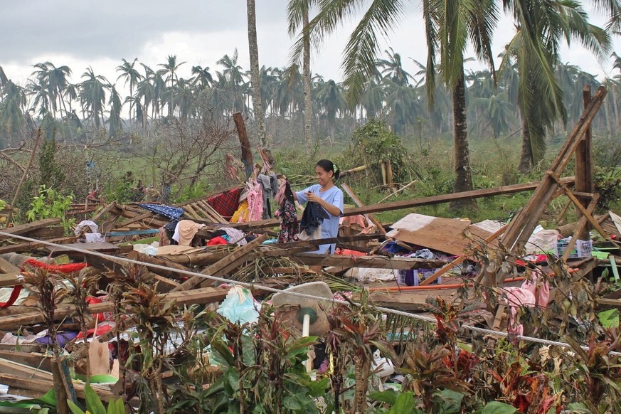 epa09649299 A handout photo made available by the Philippine Coast Guard (PCG) shows a villager collects items on a damaged house at a typhoon-hit village in the town of Carmen, Surigao del Norte prov ...