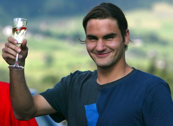 Wimbledon mens singles tennis champion Roger Federer, arriving from London, poses at the airport of Saanen near Gstaad, Switzerland, with a glass of champagne, Monday, July 7, 2003. Roger Federer will ...