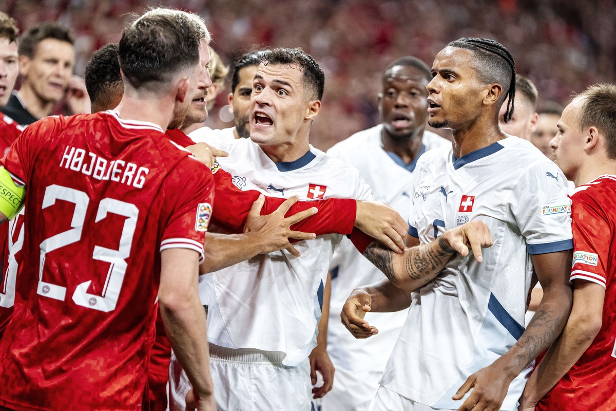 Denmark's Pierre-Emile Hoejbjerg, left, and Switzerland's Granit Xhaka, center, and Manuel Akanji tussle after Denmark's Patrick Dorgu scored during the UEFA Nations League soccer match ...