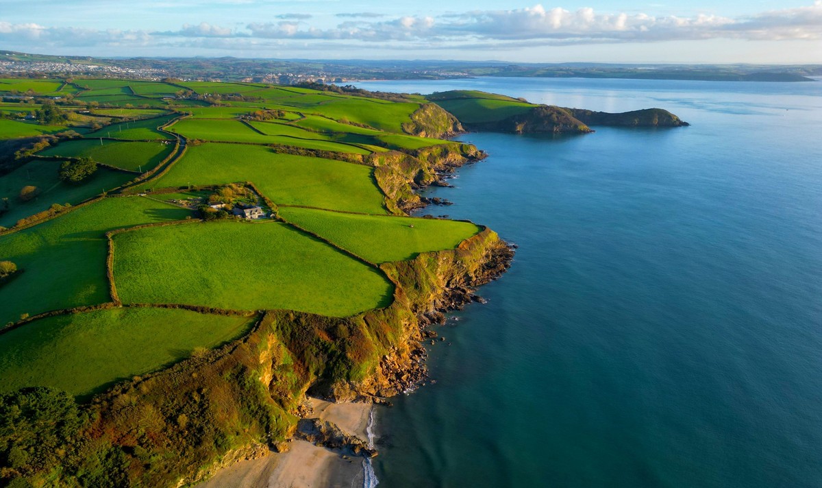 RECORD DATE NOT STATED An aerial shot of a green coastal hill in Cornish shore in front of the blue sea, Scilly Isles *** An&amp;Verkauf aerial erschossen des einer Gr