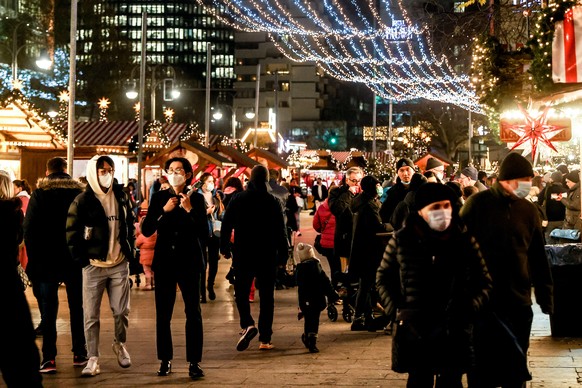 epa09602885 Visitors wear face masks at the Breitscheid square Christmas market in Berlin, Germany, 25 November 2021. Germany has reported a rising number of COVID-19 infections. EPA/FILIP SINGER
