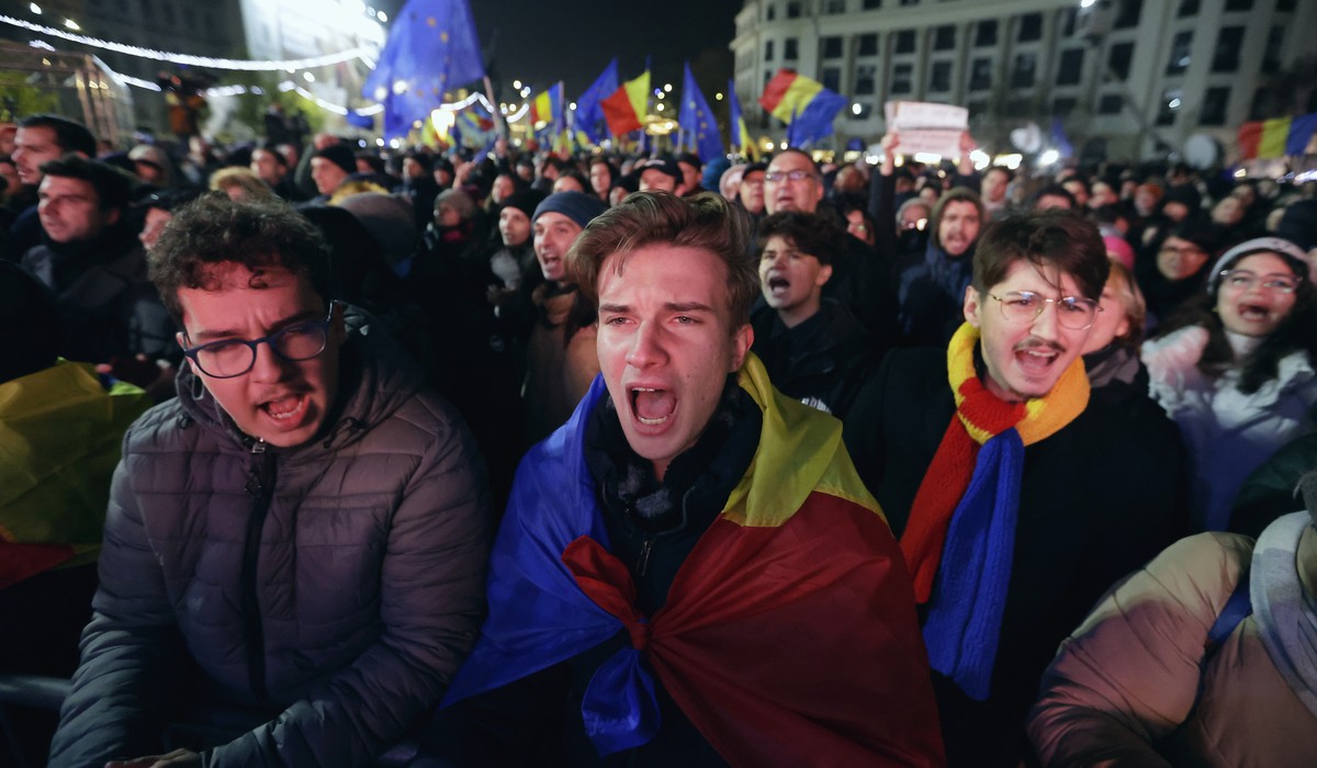 epa11759493 People sing a rock song while waving Romanian and European Union flags during a pro-Europe rally ahead of the runoff elections at the University Plaza in downtown Bucharest, Romania, 05 De ...