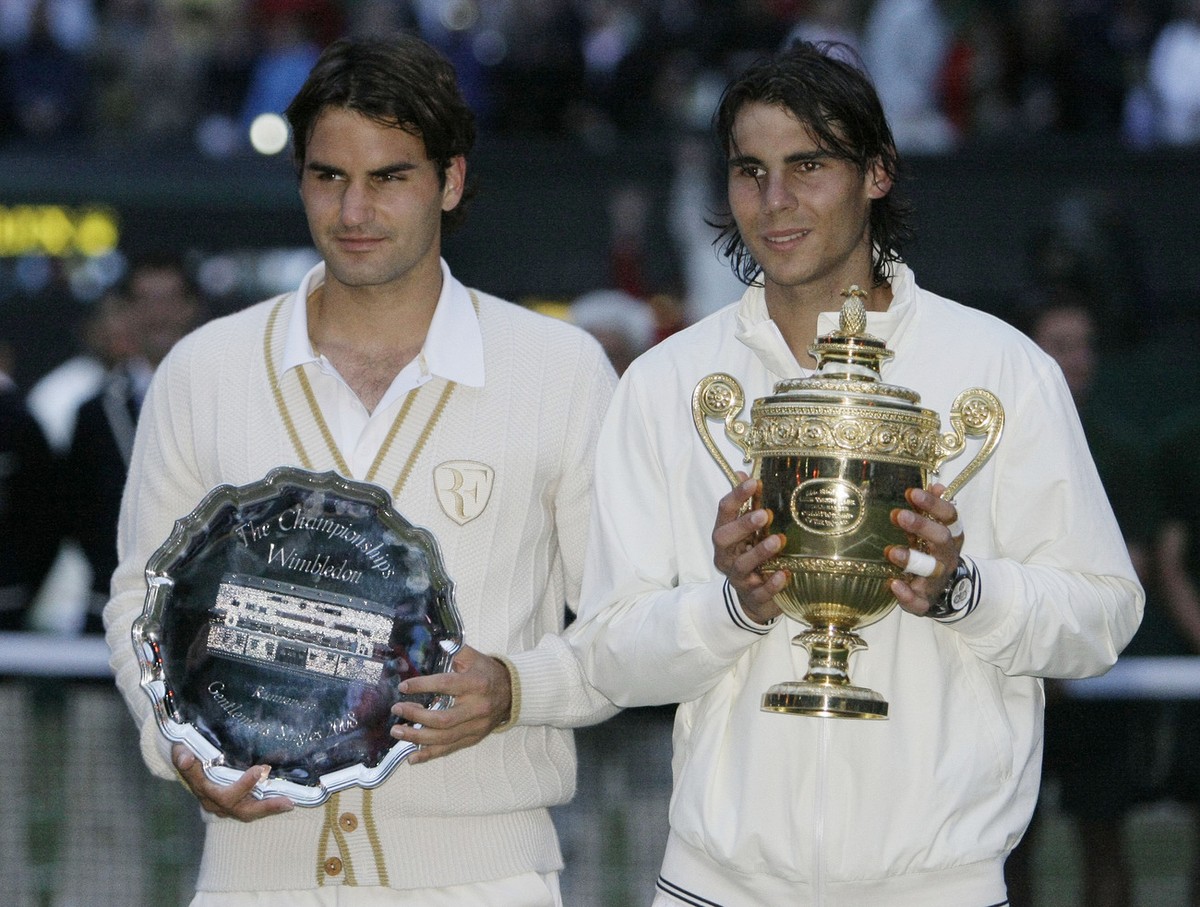 Spain's Rafael Nadal right, holds his trophy aloft as he celebrates his defeat of Switzerland's Roger Federer left, in the men's singles final on the Centre Court at Wimbledon, Sunday,  ...
