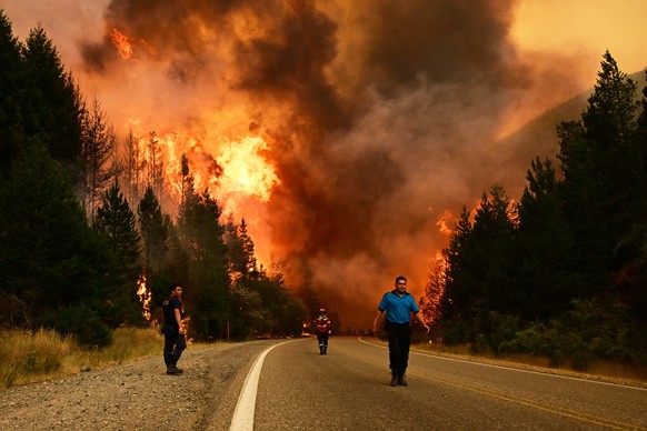 KEYPIX - People walk on a road as a wildfire blazes in El Hoyo, Patagonia, Argentina, Thursday, Jan. 8, 2026. (AP Photo/Maxi Jonas)