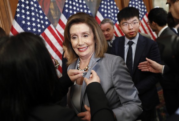 House Speaker Nancy Pelosi is given a lapel pin by a Hong Kong activist following a news conference on human rights in Hong Kong on Capitol Hill in Washington, Wednesday, Sept. 18, 2019. Behind Pelosi ...