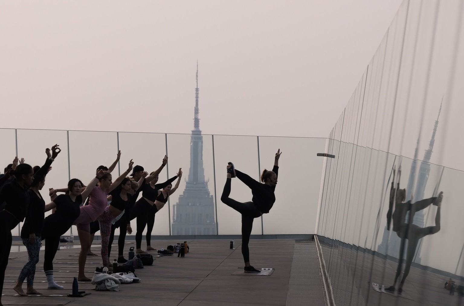 epa10677522 People attend a morning yoga class on The Edge observation deck as a haze caused by smoke from wildfires burning in Canada hangs over Manhattan in New York, USA, 07 June 2023. An air quali ...