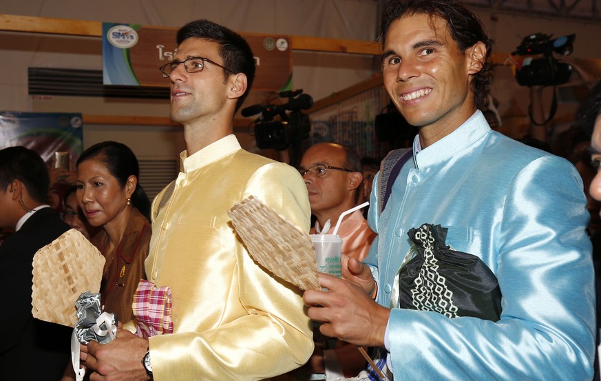 Tennis players Rafael Nadal, right, of Spain and Novak Djokovic, left. of Serbia visit a fair after meeting with Thai Prime Minister Prayuth Chan-ocha outside Government House in Bangkok, Thailand Fri ...