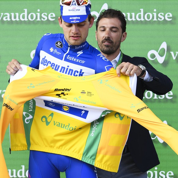 Kasper Asgreen from Denmark of Deceuninck-Quick-Step, center, poses in the yellow leader jersey, next to former Miss Switzerland Linda Faeh, left, and former racer Fabian Cancellara, right, after the  ...