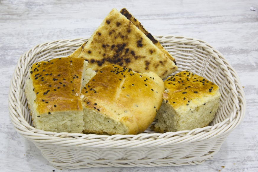 marokko frühstück brot omelette essen food Algerian homemade bread (khobz eddar) with semolina and seeds of nigella in a bread basket with white background striped gray.