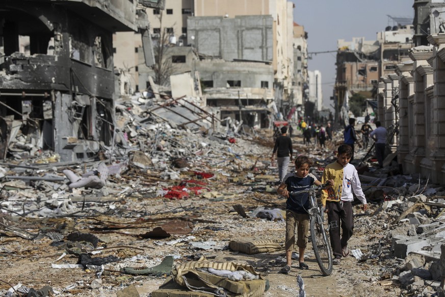 Palestinians walk through the destruction in Gaza City on Friday, November 24, 2023, as the temporary ceasefire between Israel and Hamas took effect.  (AP Photo/Mohammed Hajjar)