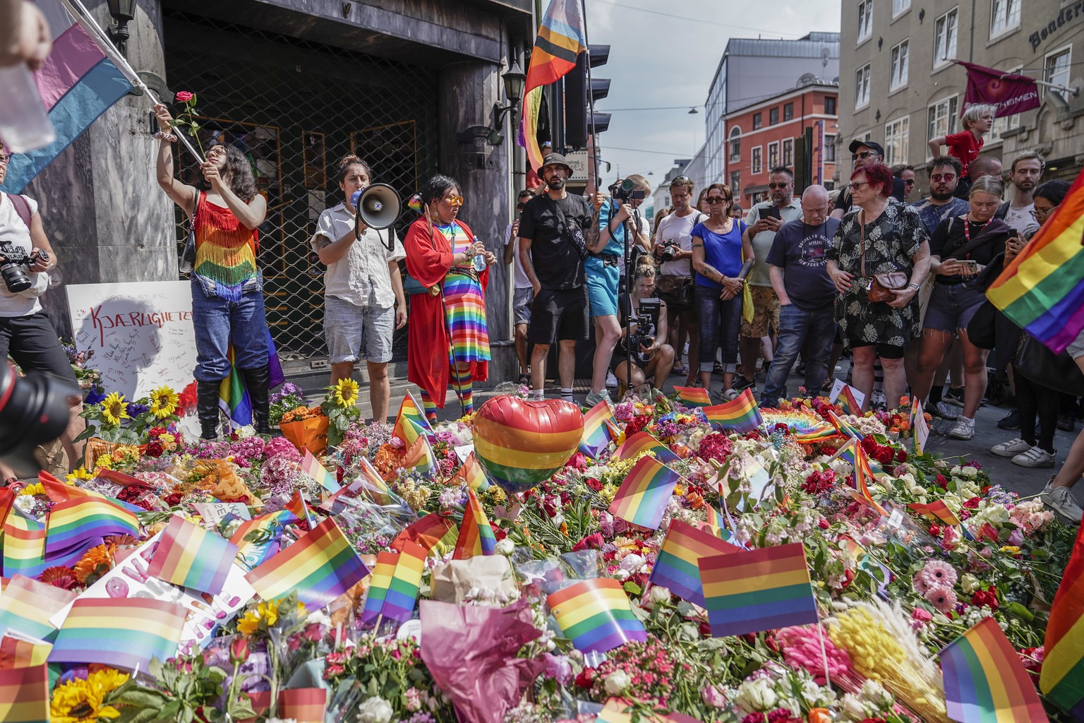 Flowers are left as a spontaneous pride parade arrives at the scene of a shooting in central Oslo, Saturday, June 25, 2022. Norwegian police say they are investigating an overnight shooting in Oslo th ...