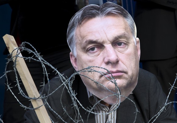 An Avaaz&#039;s activist wears a mask depicting Hungary&#039;s Prime Minister Viktor Orban behind barbed wire during a demonstration in support of asylum seekers in Brussels September 14, 2015. Divide ...