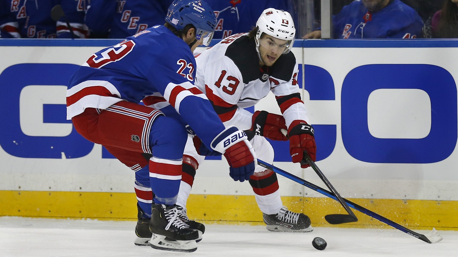 New York Rangers&#039; Adam Fox (23) and New Jersey Devils&#039; Nico Hischier (13) battle for the puck during the first period of an NHL hockey game Sunday, Nov. 14, 2021, in New York. (AP Photo/John ...