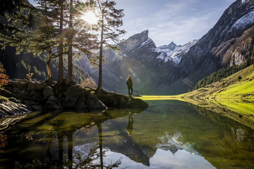 epa06289138 A hiker enjoys the view of the mountain Saentis at the Seealpsee lake, in the canton of Appenzell Innerrhoden, Switzerland, on 25 October 2017. EPA/CHRISTIAN MERZ