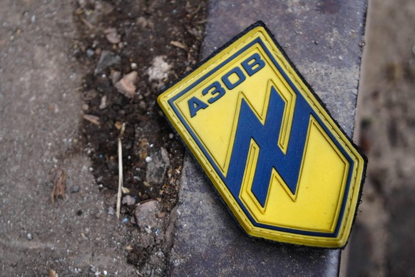 Auf einer Strasse in Mariupol liegt ein Abzeichen mit dem Logo des «Asow»-Bataillons.
