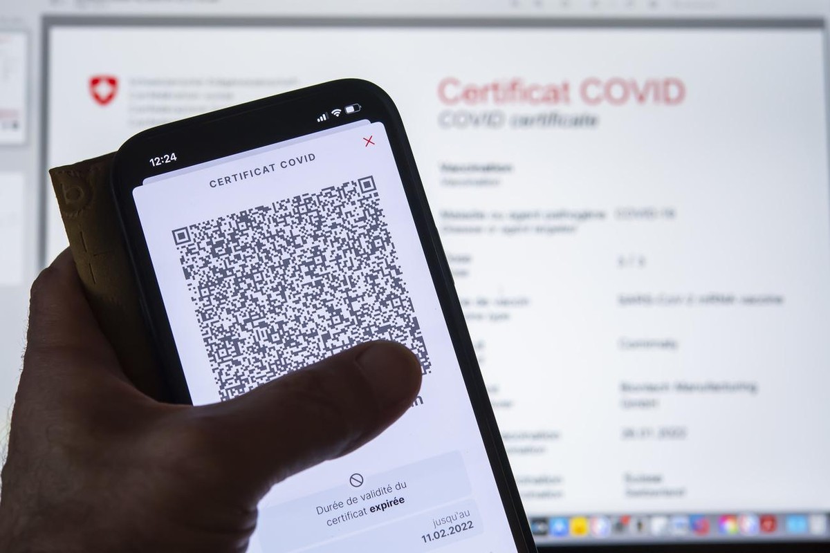 Une personne tient dans sa main un smartphone avec l'application Certificat Covid suisse et son code QR ou il est inscrit "Duree de validite du certificat expiree. Ce certificat ne repond pa ...