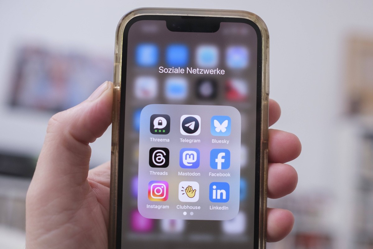 Eine Hand hält ein Mobiltelefon auf dem die Logos von verschiedenen social media Anbietern zu sehen sind *** Hand holds a mobile phone on which the logos of various social media providers can be seen  ...