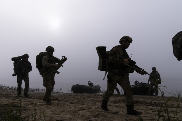 FILE - Ukrainian servicemen walk on the shore of Dnipro river after exiting a boat at the front line near Kherson, Ukraine, Sunday Oct. 15, 2023. A gloomy mood hangs over Ukraine?s soldiers nearly two ...