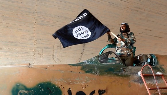 Ein Kämpfer der Terrormiliz Islamischer Staat (IS) mit einer Flagge. (Symbolbild)