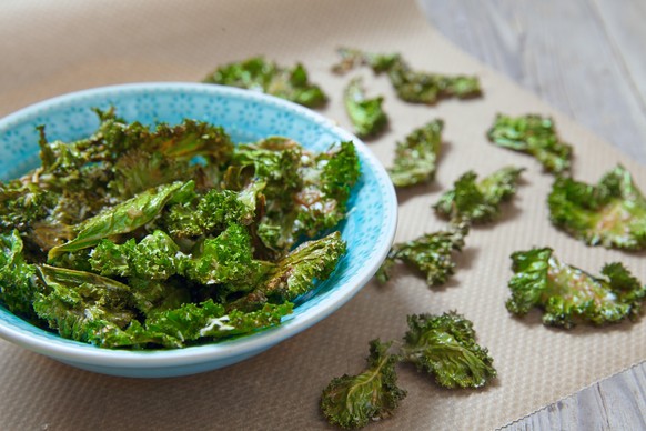 Kale chips with parmesan cheese on wooden table