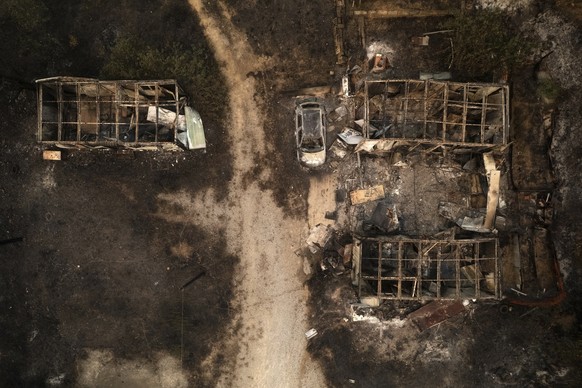 A burnt car and warehouses are seen from above in the village of Palagia, near Alexandroupolis town, in the northeastern Evros region, Greece, Tuesday, Aug. 22, 2023. Hundreds of firefighters struggle ...