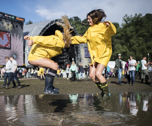 epaselect epa06058496 Visitors jump in a puddle during the 41st Openair St. Gallen music festival, in St. Gallen, Switzerland, 30 June 2017. The festival runs from 29 June to 02 July. EPA/ENNIO LEANZA