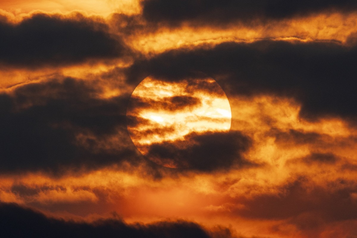 This photograph shows the sun setting with an orange haze, at sunset in Ablain-Saint-Nazaire, northern France, on June 3, 2025. Large smoke plumes caused by violent and early wildfires in Canada have  ...
