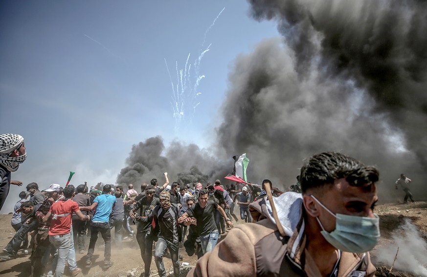 epa06737562 Palestinian protesters run for cover from Israeli tear-gas during clashes after protests near the border with Israel in the east of Gaza Strip, 14 May 2018 (issued 15 May 2018). More prote ...