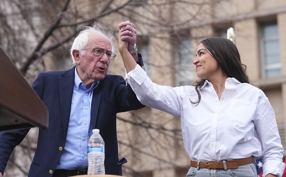 FILE _ Sen. Bernie Sanders, I-Vt., left, greets Rep. Alexandria Ocasio-Cortez, D-N.Y., as they speak during a stop of their &quot;Fighting Oligarchy&quot; tour at Civic Center Park, March 21, 2025, in ...