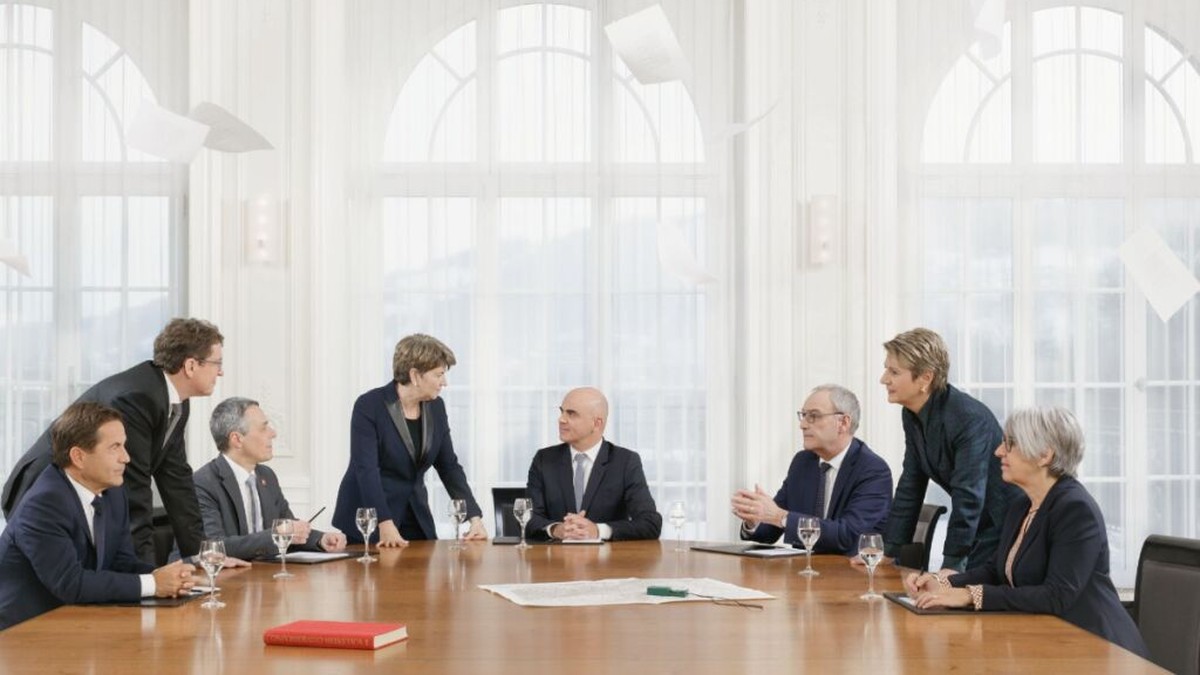 "Dans une période d’incertitudes et de crises, la photographie doit être à la fois rassurante et sobre. Elle entend montrer l’unité du Conseil fédéral et la bonne collaboration de ses membres, ma ...