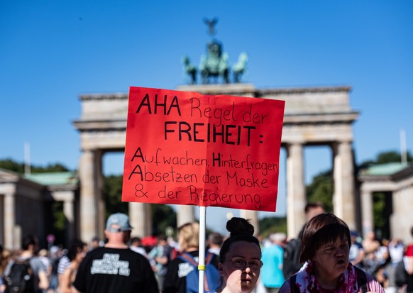 01.08.2020, Berlin: Ein Schild mit der Aufschrift &quot;AHA Regel der Freiheit: Aufwachen, Hinterfragen, Absetzen der Maske &amp; der Regierung&quot; ragt aus der Menschenmenge bei der Demonstration g ...