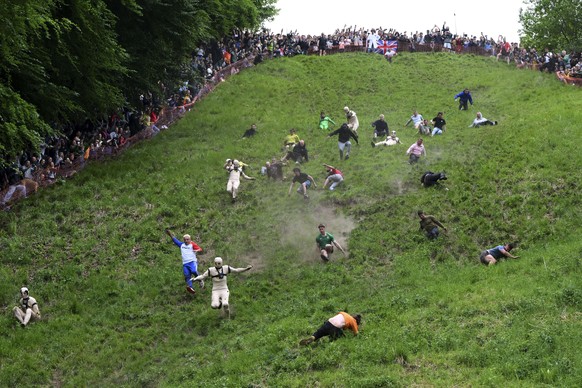 Participants, some dressed as a &quot;crash test dummies&quot; in a morph suits, compete in the men&#039;s downhill race category of the traditional annual Cheese Rolling contest at Cooper&#039;s Hill ...